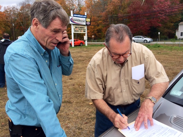 Glastonbury businessman Bruce Bemer (left) fills out paperwork with attorney Garon Camassar after Bemer was the high bidder in a foreclosure auction Saturday of the Waterford Speedbowl  